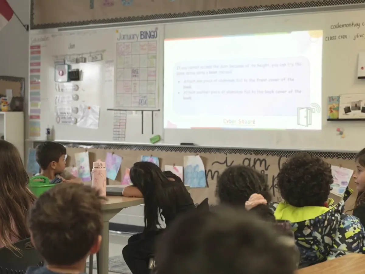 Students follow a coding lesson on the classroom screen